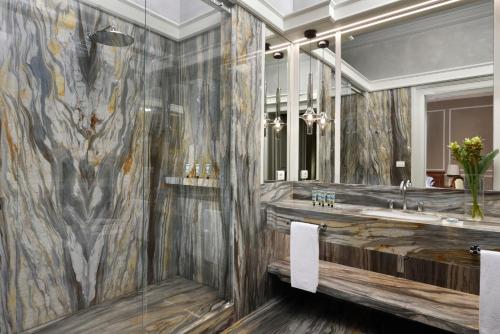 a bathroom with a sink, mirror, and bathtub at Villa Cortine Palace Hotel in Sirmione
