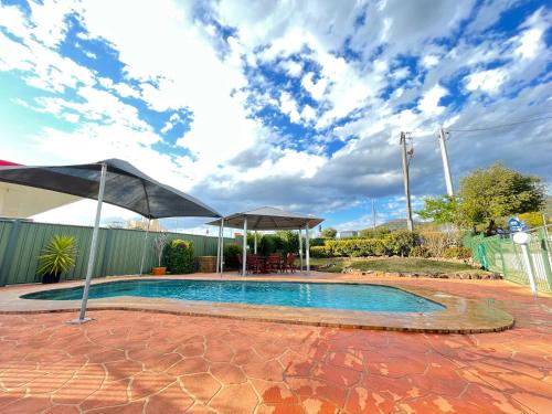 a swimming pool with an umbrella and a patio at City Sider Motel in Tamworth