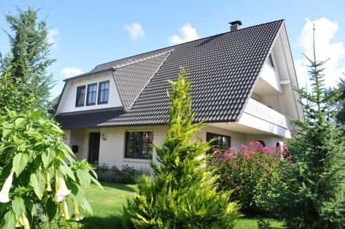 uma casa com um telhado preto e algumas árvores em Schippers Butz strandnah mit Whirpool em Ostseebad Karlshagen