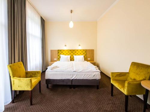 a hotel room with a bed and two chairs at Villa Anna Lisa in Świnoujście