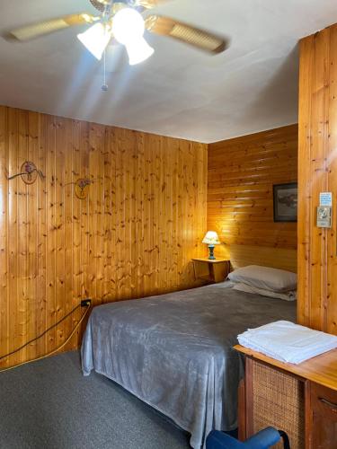 1 dormitorio con paredes de madera, 1 cama y techo en Hillcrest Motel, en Saint John