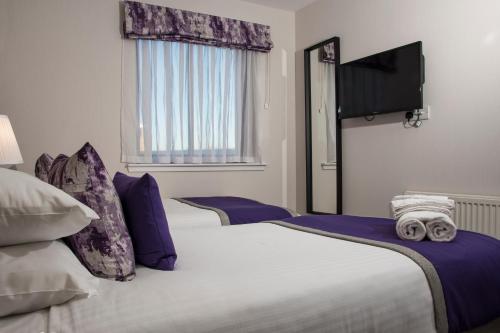 two beds in a hotel room with purple pillows at The Knight Residence by Mansley in Edinburgh