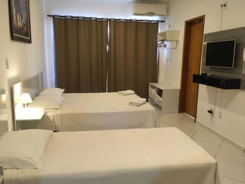 a hotel room with two beds and a television at Domum Hotel in Pindamonhangaba