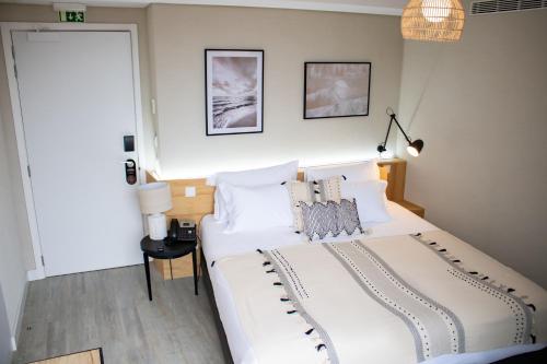 a bedroom with a large white bed with white pillows at Kavia Hotel do Largo in Cascais