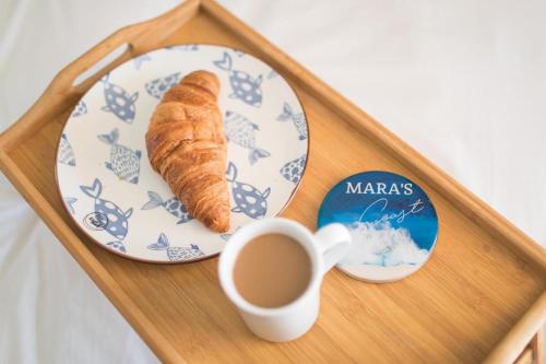 ein Tablett mit einem Teller mit einem Croissant und einer Tasse Kaffee in der Unterkunft Mara's Coast - Frida in Drage