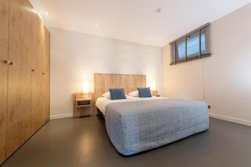 una camera da letto con un grande letto con cuscini blu di Droomvakanties Egmond Appartement van Speijk a Egmond aan Zee