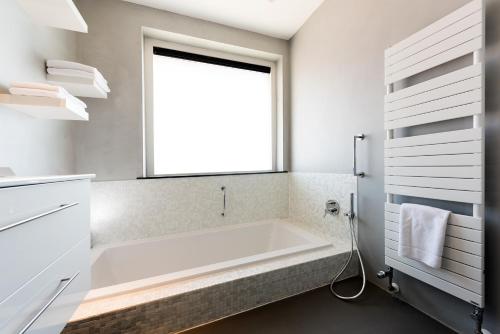a bathroom with a large tub and a window at Droomvakanties Egmond Appartement van Speijk in Egmond aan Zee