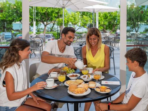 a family sitting around a table eating breakfast at Hotel Leonardo Da Vinci in Limone sul Garda