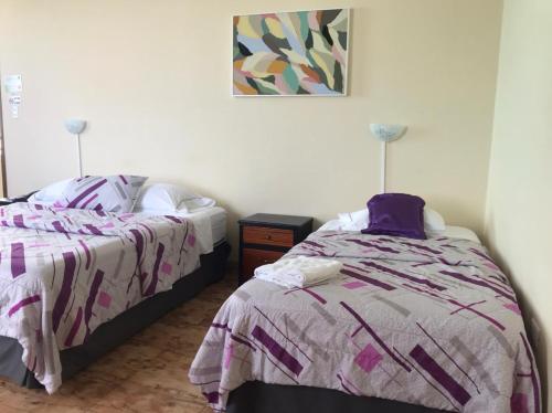 Hotel Las Palmas في إسمرالداس: غرفة نوم بسريرين وصورة على الحائط