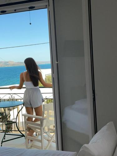 a woman standing on a chair looking out the window at the ocean at Studios Angeliki in Lassi