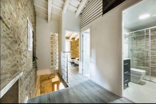 a bathroom with a toilet and a stone wall at The Yellow House by MyRentalHost in Barcelona