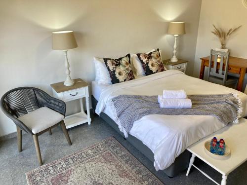 a bedroom with a bed and a chair and a table at Tidor Garden Cottage in Bloemfontein