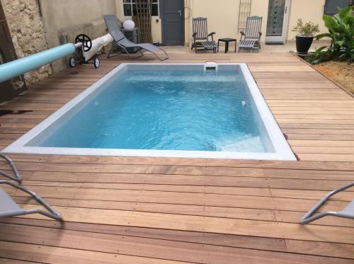- une piscine sur une terrasse en bois avec des chaises dans l'établissement Au Plaisir d Etape- Gîte touristique Condom, à Condom