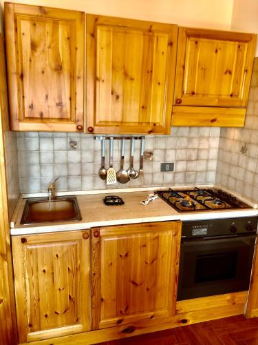 a kitchen with wooden cabinets and a stove and a sink at Casa serenaurora in Castel di Sangro
