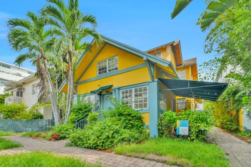 een geel en blauw huis met palmbomen bij Sunflower Boutique Hotel Apartments in Miami Beach