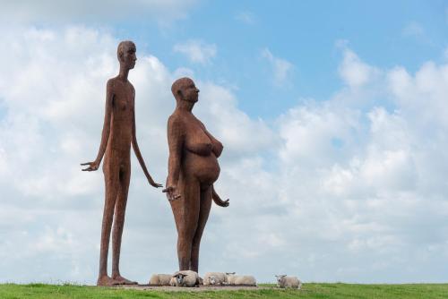 a statue of two people and sheep on a field at Thús yn Hantum in Hantum