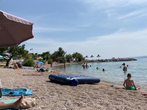 a group of people on a beach near the water at Apartments Mali Val in Punat
