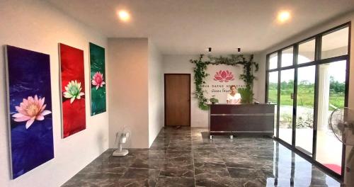 a hallway with paintings on the wall and a woman in a room at Bua Daeng Homestay Resort in Amphoe Kumphawapi