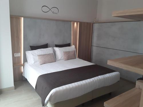 a bedroom with a large bed with white sheets and pink pillows at Hotel Danieli La Castellana lago di Garda in Brenzone sul Garda