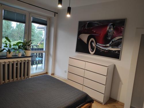 a bedroom with a bed and a painting of a car on the wall at Apartament Pod Taborem in Niedzica Zamek