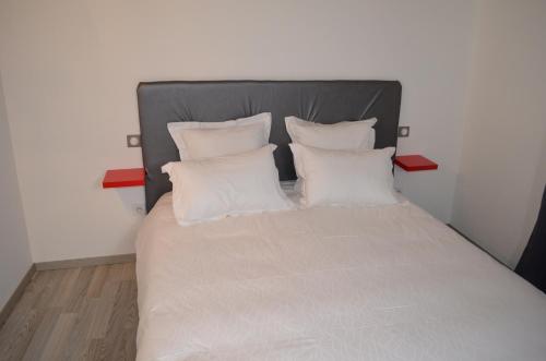 a bed with white pillows and a gray headboard at La Petite Ecole in Marciac