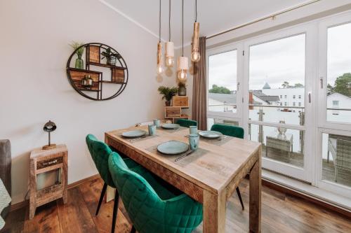 a dining room with a wooden table and green chairs at Sonne-Strand-Binz in Binz