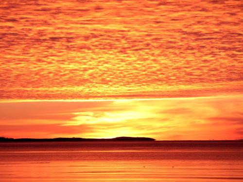 een zonsondergang boven het water met de hemel bij Seawind Landing Country Inn in Larrys River