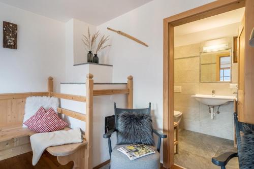 a bathroom with a sink and a toilet and a chair at Thaler-hof Ferienhaus Fichtnhittl in Lagundo