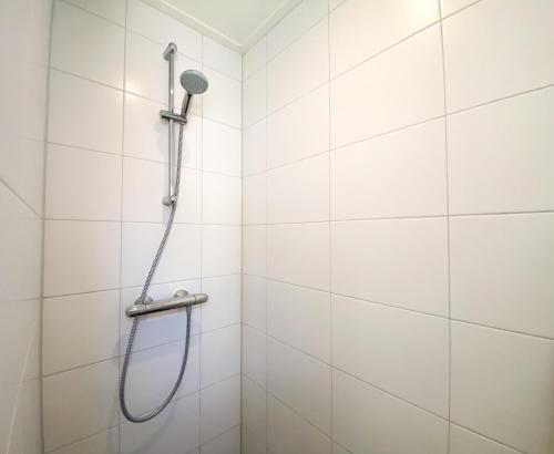 y baño con ducha y azulejos blancos. en Vakantiehuis de Strandloper Serooskerke Se08, en Serooskerke