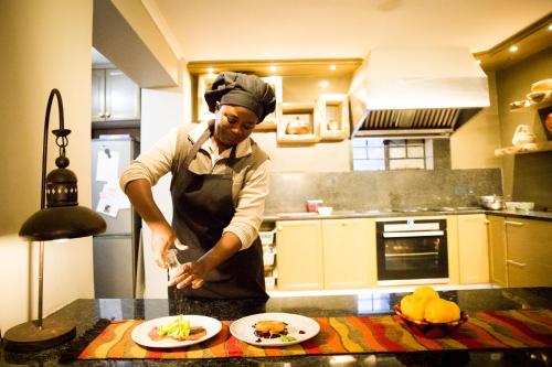 a man standing in a kitchen preparing food at Olive Grove Guesthouse in Windhoek