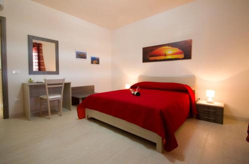 a bedroom with a red bed and a table at Villa del Vento in Birgi Vecchi