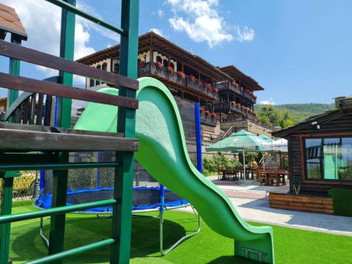 a playground with a green slide at a resort at Leshtenski Rai Guest House in Leshten