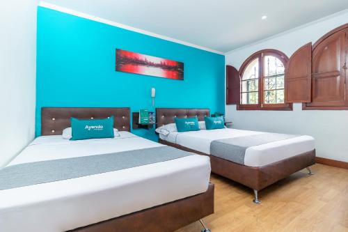 two beds in a room with blue walls at Ayenda Palermo Plaza in Bogotá