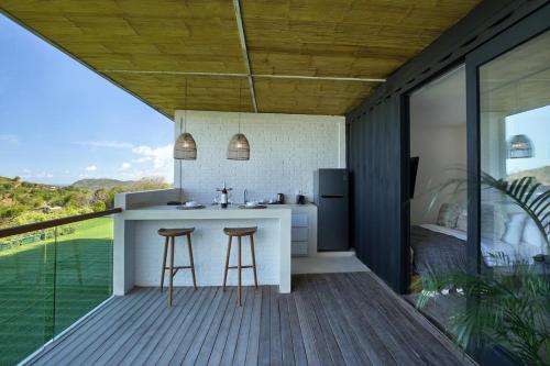 a kitchen with a counter and stools on a deck at Telescope Resort Lombok in Kuta Lombok
