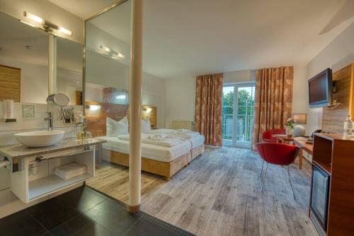 Hotel & SPA Reibener-Hof في Konzell: غرفة نوم بسرير ومغسلة ومرآة