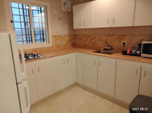 a kitchen with white cabinets and a sink and a window at فندق الحاتمية in Abha
