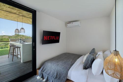 a bedroom with a bed and a balcony with a sink at Telescope Resort Lombok in Kuta Lombok