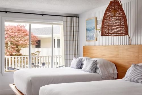 two beds in a bedroom with a view of a porch at Bluebird Parker Beach Lodge in South Yarmouth