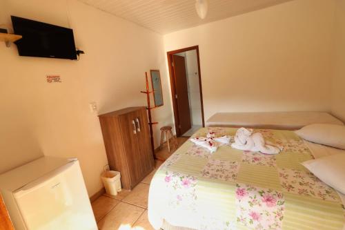 a bedroom with a bed with two dolls on it at Pousada Pé da Serra in Lindóia