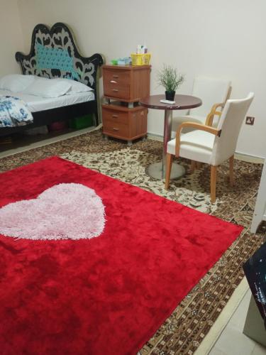 a red rug in a room with a bed and a table at Room with attached bathroom in Al 'Ayn