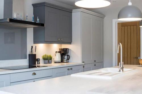 a kitchen with white cabinets and a white sink at Green Ridge - detached seaside home in Chichester