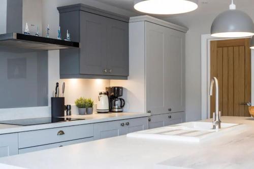 a kitchen with white cabinets and a white sink at Green Ridge, luxury seaside residence in Chichester