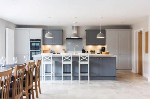 a kitchen with blue cabinets and a kitchen island with chairs at Green Ridge - detached seaside home in Chichester