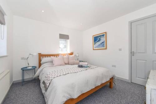 a white bedroom with a large bed with pink pillows at The Little House, boutique home near the sea in Chichester