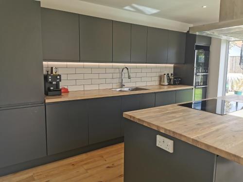uma cozinha com armários cinzentos e um balcão de madeira em Iona 4 bed luxury in the heart of Bracklesham Bay em Chichester