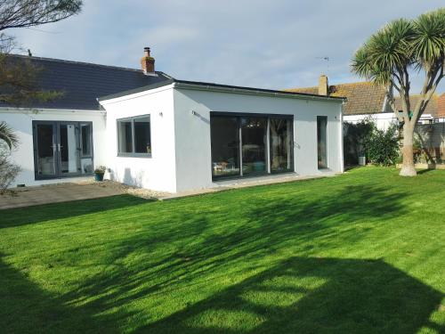a white house with a green yard at Iona – Bracklesham Bay in Chichester