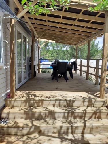 - une terrasse couverte avec une table et un banc dans l'établissement Mobil home 6 personnes - Camping les jardins du littoral, à Lacanau