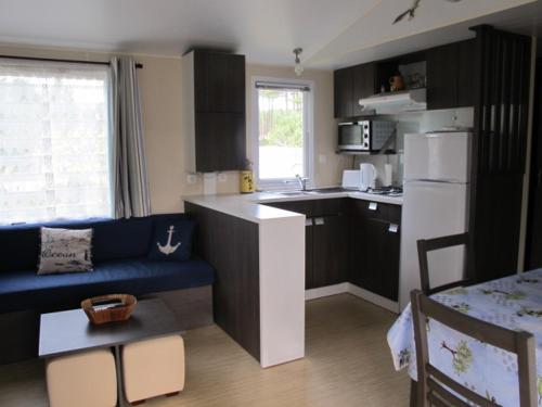 une cuisine avec un canapé bleu dans une petite cuisine dans l'établissement Mobil home 6 personnes - Camping les jardins du littoral, à Lacanau