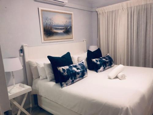 1 dormitorio con 1 cama con almohadas azules y blancas en Sands Beach Breaks Umdloti Beach View, en Umdloti