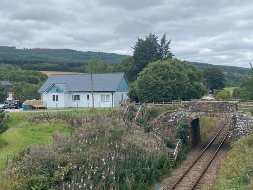 a white house and a bridge with a building at Linne Lodge in Tain